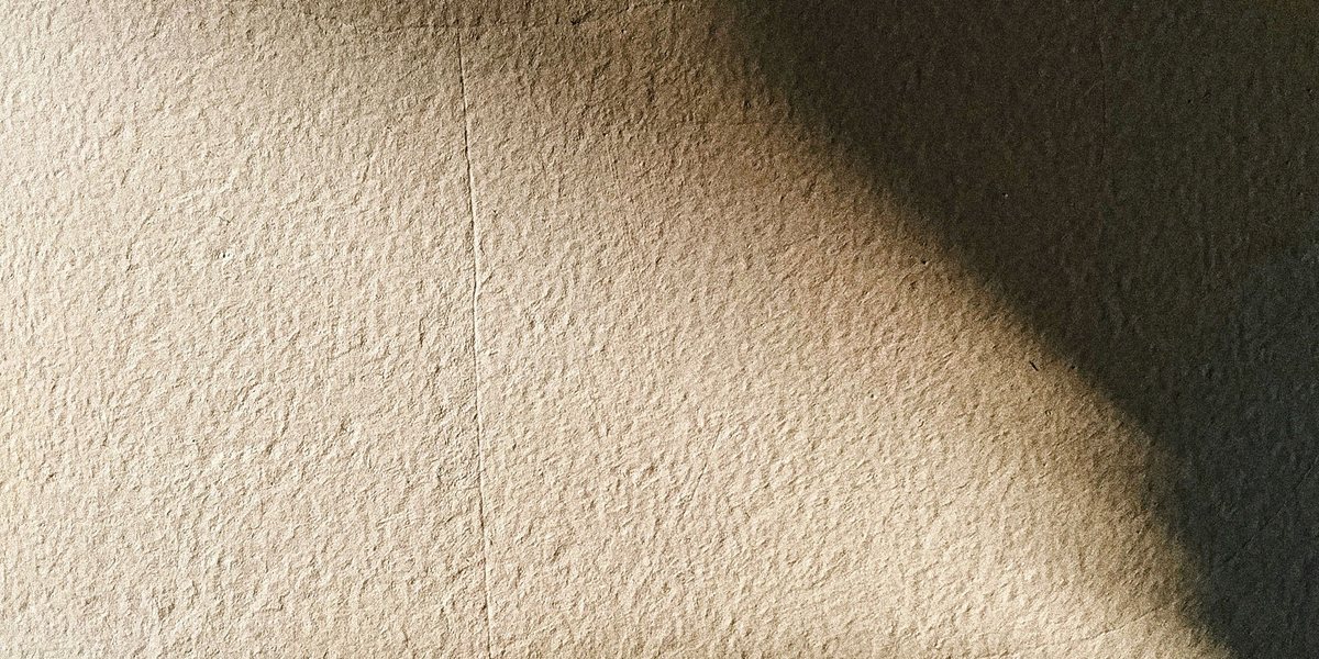 Textured plaster wall with a soft diagonal shadow